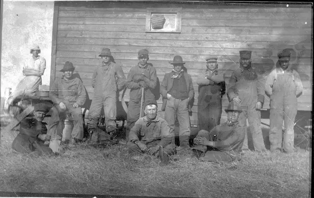 Harvesting crew posed beside a wooden building